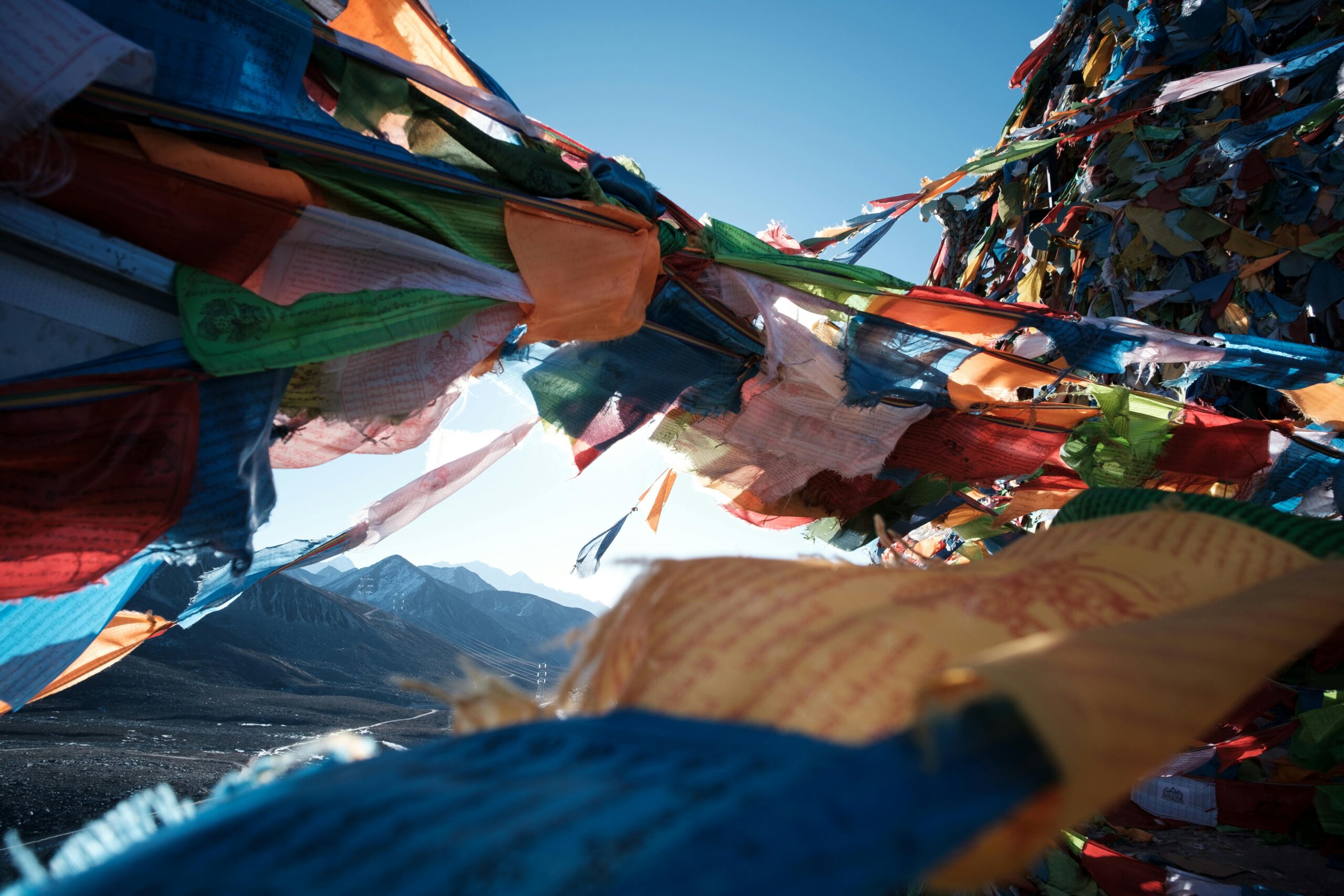 Vibrant prayer flags waving in the wind with stunning mountain backdrop.